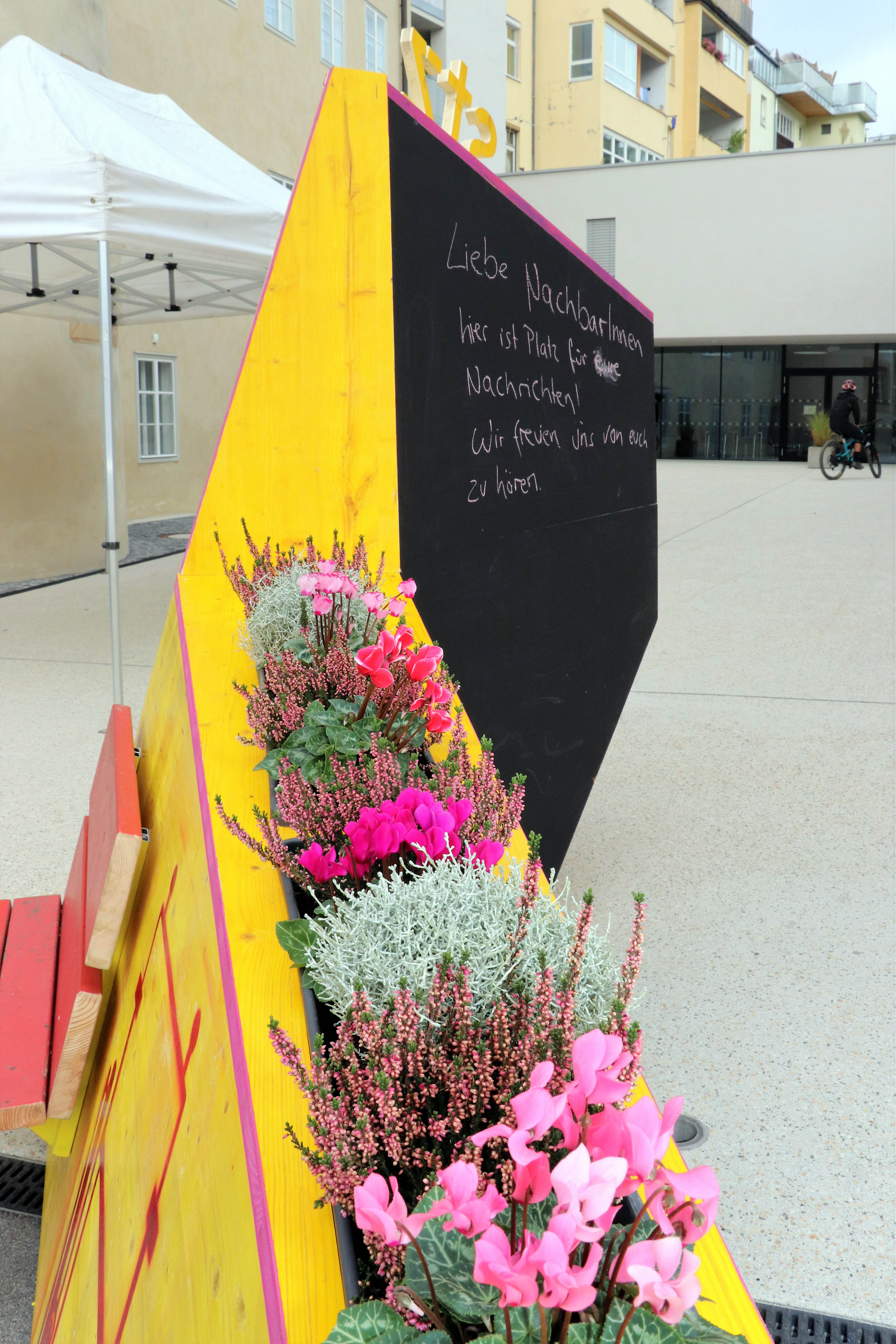 Kreativ, bunt und unübersehbar – so präsentiert sich seit 4. Oktober das temporäre, öffentliche Möbelstück vor dem Stadtteilzentrum Wilten in der Leopoldstraße 33a. Die Idee für das hölzerne Bauwerk entstand im Rahmen eines Beteiligungsprozesses bereits im Dezember 2017. Damals kamen NachbarInnen, ein Kreativteam aus Wilten und VertreterInnen des Stadtteilzentrums zusammen, um über die Gestaltung des Innenhofes zu beratschlagen. Die nun realisierte Konstruktion enthält die gewünschten Elemente, bestehend aus Beschriftung, Informations- und Plakatflächen, einem Buchtauschregal, Sitzgelegenheiten und kann mit Blumentöpfen ausgestattet werden. Bei der Einweihung kamen viele Beteiligte und UnterstützerInnen zusammen, unter ihnen auch Gemeinderätin Janine Bex, Geschäftsführer Hubert Innerebner (Innsbrucker Sozialen Dienste, ISD), Stadtteilkoordinatorin Florence Fritz sowie das Kreativteam rund um Charly Walter und zahlreiche AnrainerInnen. Bis Juni 2021 lädt das öffentliche Möbelstück vor dem Stadtteilzentrum Wilten zum Verweilen und Verwenden ein. AA