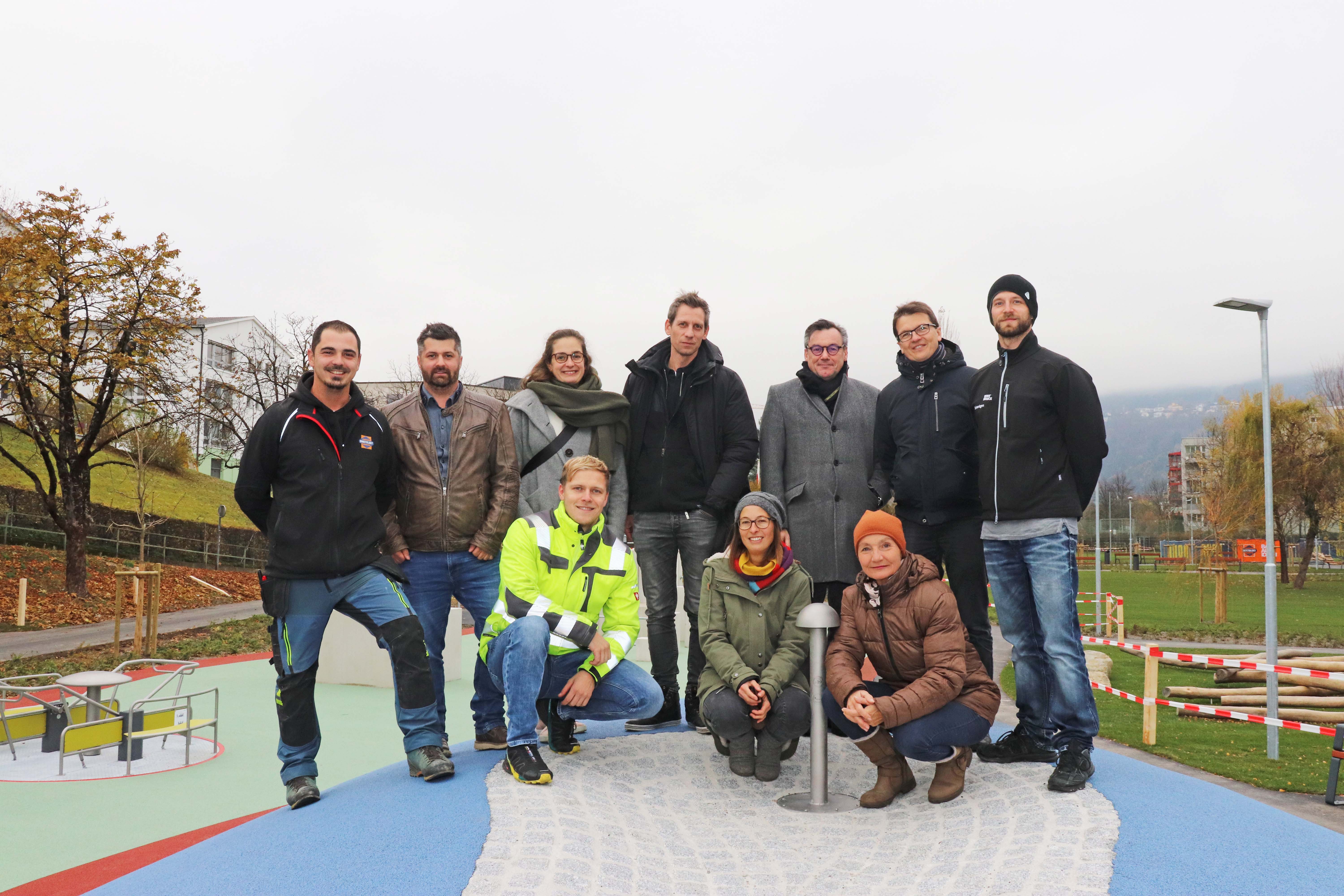 Freuten sich über die Fertigstellung des Grünzugs: Bauleiter Christopher Knabl (Swietelsky; 2. v. l.), Landschaftsarchitekt Kieran Fraser (M.), Markus Pollo (GF Neue Heimat Tirol; 3. v. r.), Markus Pinter (Grünanlagen – Planung und Bau; 2. v. r.) mit Team, und Vizebürgermeisterin Uschi Schwarzl (vorne r.)
