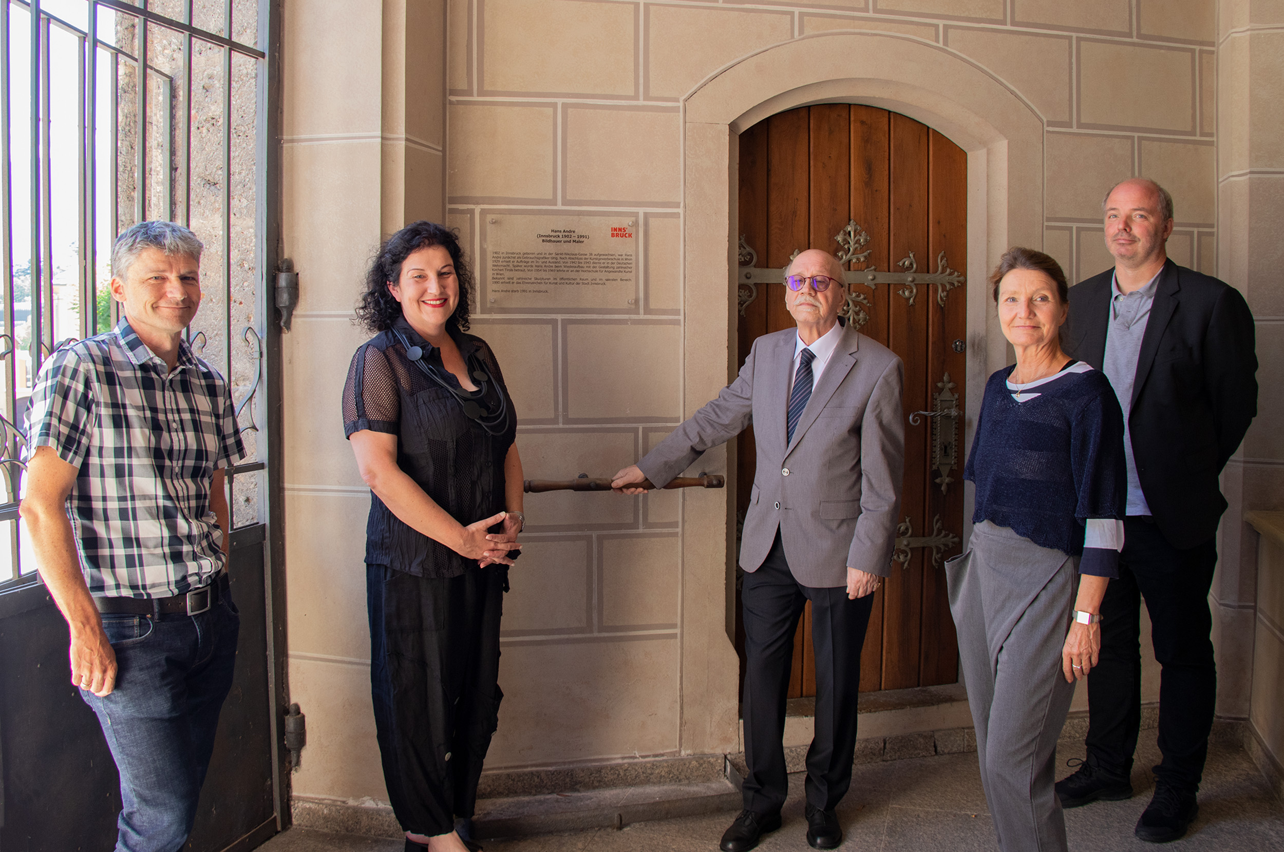 Eine städtische Erinnerungstafel an den Innsbrucker Künstler Hans Andre im Vorraum der Pfarrkirche St. Nikolaus: Sie wurde in Anwesenheit von Vizebürgermeisterin Uschi Schwarzl (4. v. l.) und (von links) Klaus Spielmann (Pfarrkirche St. Nikolaus), Gemeinderätin Irene Heisz, Renatus Leimgruber (Neffe des Künstlers) und Lukas Morscher (Stadtarchiv/Stadtmuseum Innsbruck) der Öffentlichkeit übergeben.