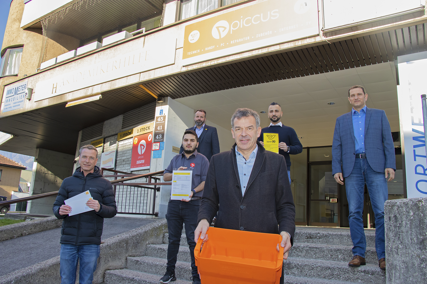 Die BewohnerInnen im Olympischen Dorf haben in ihrem Stadtteil wieder eine Poststelle. Der Handyshop PICCUS hat kürzlich eine Filiale in der Schützenstraße 41 gegenüber der Polizeiinspektion Neu-Arzl eröffnet und wird dort eben auch Postpartner-Dienste anbieten. Die beiden Geschäftsführer Alkim Isik (2. v. l.) und Emre Günal (Mitte oben) freuen sich gemeinsam mit Bürgermeister Georg Willi, Gemeinderat und Präsident des ortsansässigen Verbandes Neu-Arzl/Olympisches Dorf (VNO) Christoph Kaufmann (1. v. l.) sowie Gerhard Hainz (Verkaufsleiter Tirol, Österreichische Post AG, oben links) und Thomas Bramberger (Change-Management Mitte West, Österreichische Post AG, oben rechts) über die Inbetriebnahme des Postpartner-Shops.