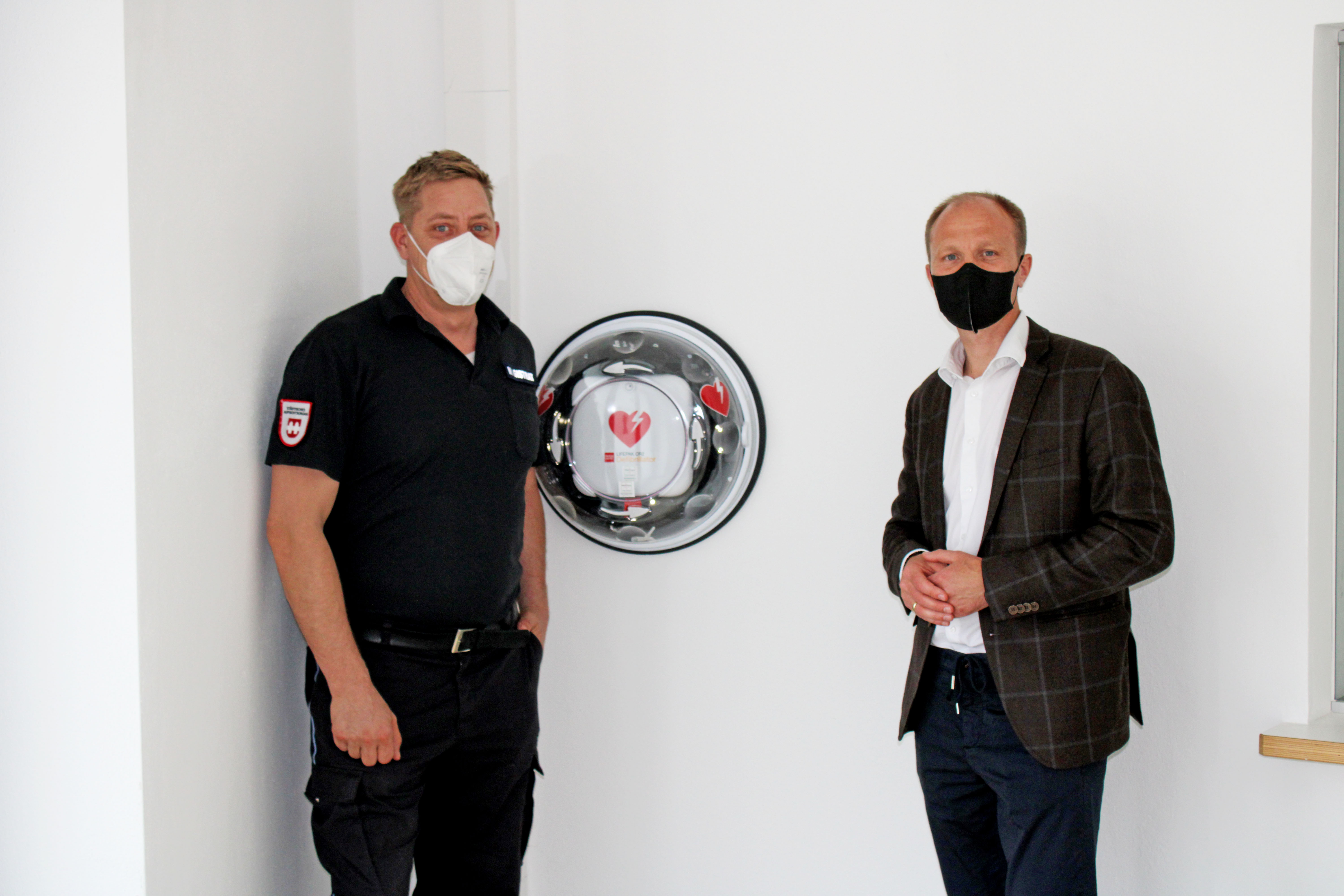 Vizebürgermeister Anzengruber (r.) und MÜG-Mitarbeiter Thomas Hintersdorf vor dem neu angebrachten Defibrillator.