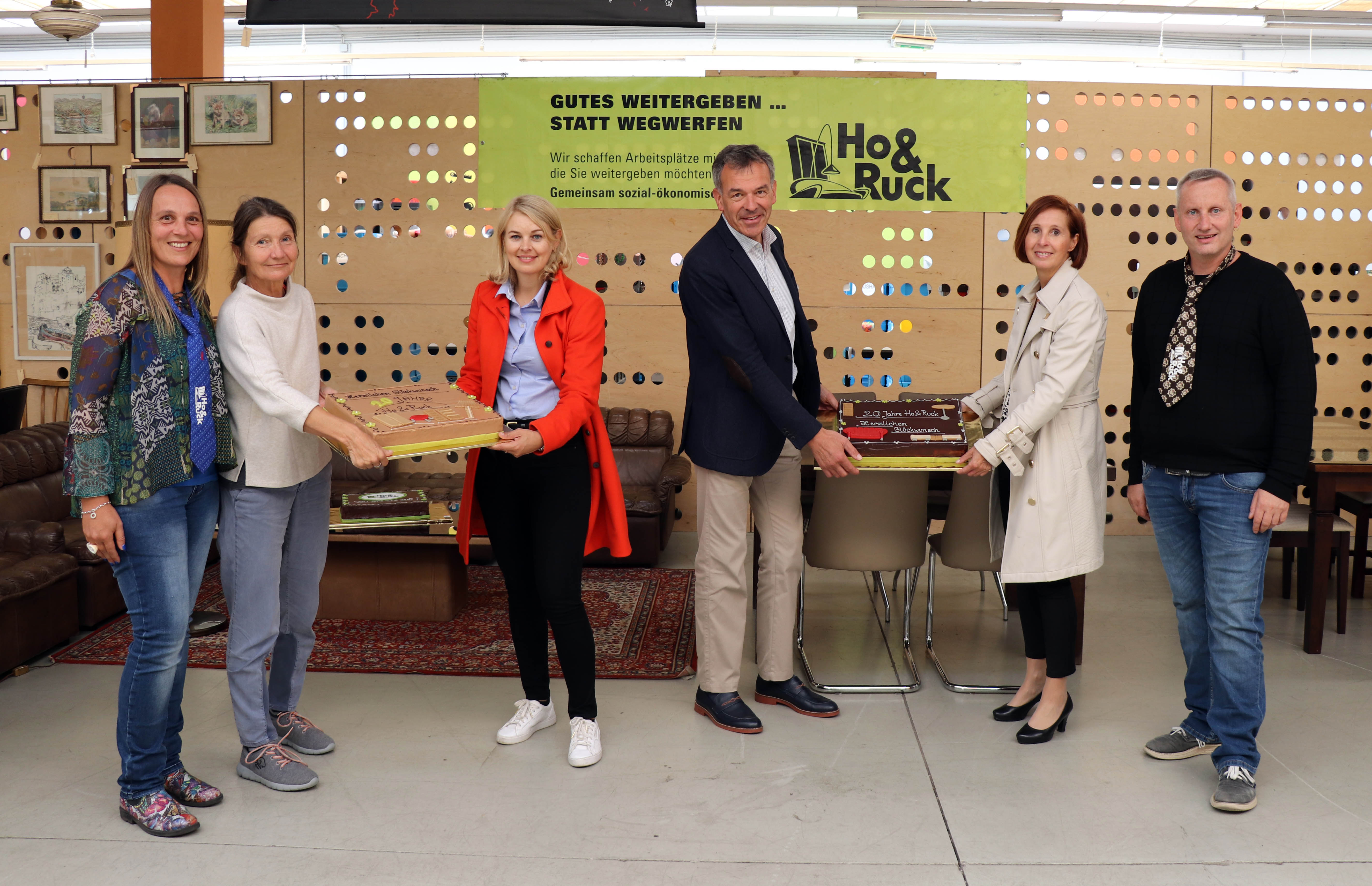 Seit genau 20 Jahren ist das gemeinnützige Unternehmen Ho&Ruck in der ehemaligen Lodenfabrik an der Hallerstraße beheimatet und hat sich zu einer Institution in Innsbruck entwickelt. Bürgermeister Georg Willi (3. v. r.) gratulierte gemeinsam mit den beiden Stadträtinnen Elisabeth Mayr (3. v. l.) und Uschi Schwarzl (2. v. l.) sowie Landesrätin Gabriele Fischer (2. v. r.) anlässlich des runden Jubiläums. Als kleine Aufmerksamkeit überreichten sie zwei prachtvolle Torten an die beiden GeschäftsführerInnen Martina Wolf-Kuntner und Thomas Holzer.