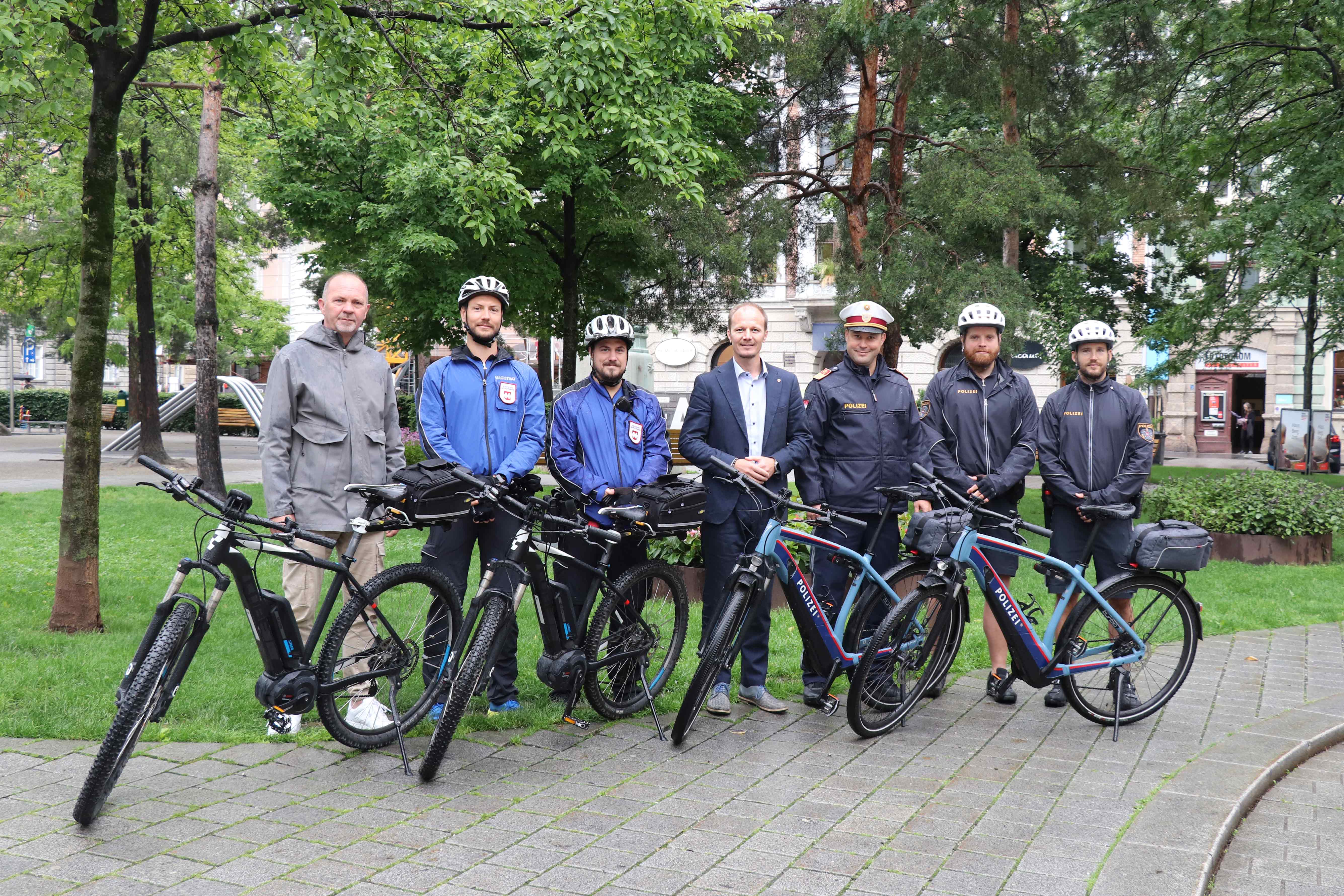 Thomas Koland vom Referat für Öffentliche Ordnung, Vizebürgermeister Johannes Anzengruber und Stv. Stadtpolizeikommandant Daniel Mallaun präsentieren mit jeweils zwei Bediensteten der MÜG und der Stadtpolizei ihre Einsatz-E-Bikes.