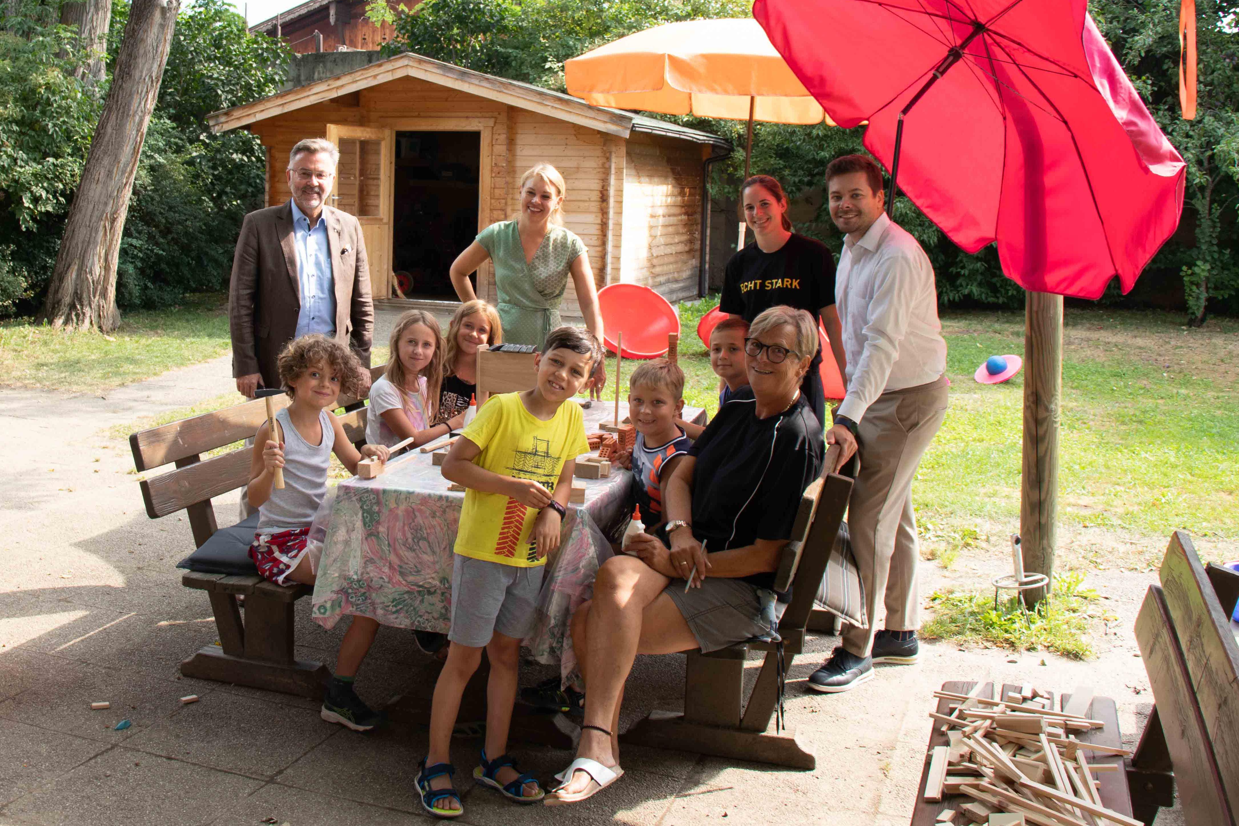 Rüdiger Lex (proHolz Tirol) und Stadträtin Elisabeth Mayr freuen sich mit Alina Priß (BAUAkademie Tirol), Daniel Bonora-Burgstaller (Referat Bildungsservicestelle) und Hortbetreuerin Michaela Schmiedlechner über die Baukünste der Kinder im Sommerhort Domanigweg.