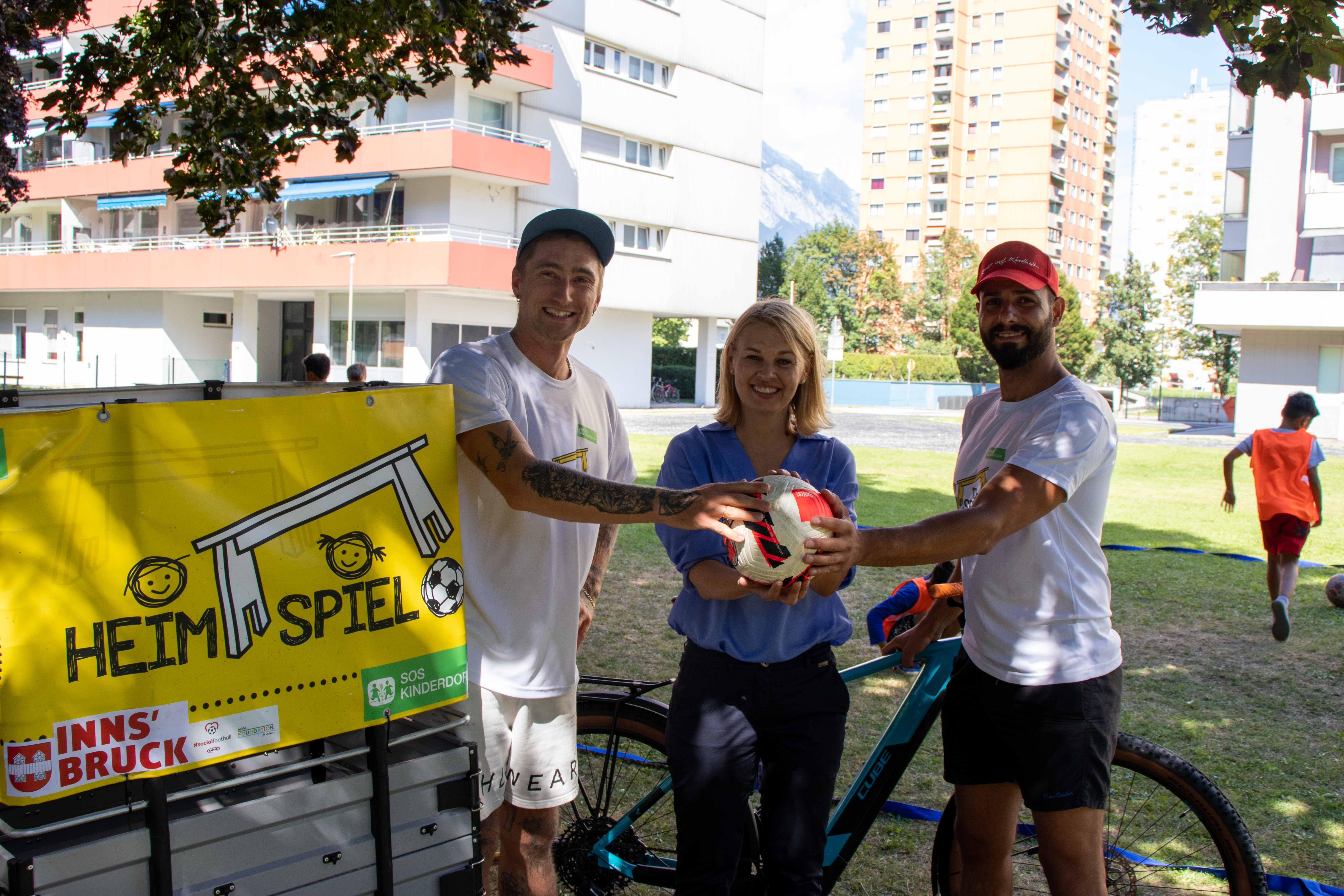 Stadträtin Elisabeth Mayr freut sich mit den zwei Sportpädagogen des SOS-Kinderdorf Dennis Höpfel (1.v.l) und Asad Zaki (3.v.l) über die zahlreichen Kinder, die das Sportangebot des „Heimspiel“-Projektes mit großer Freude nutzen.