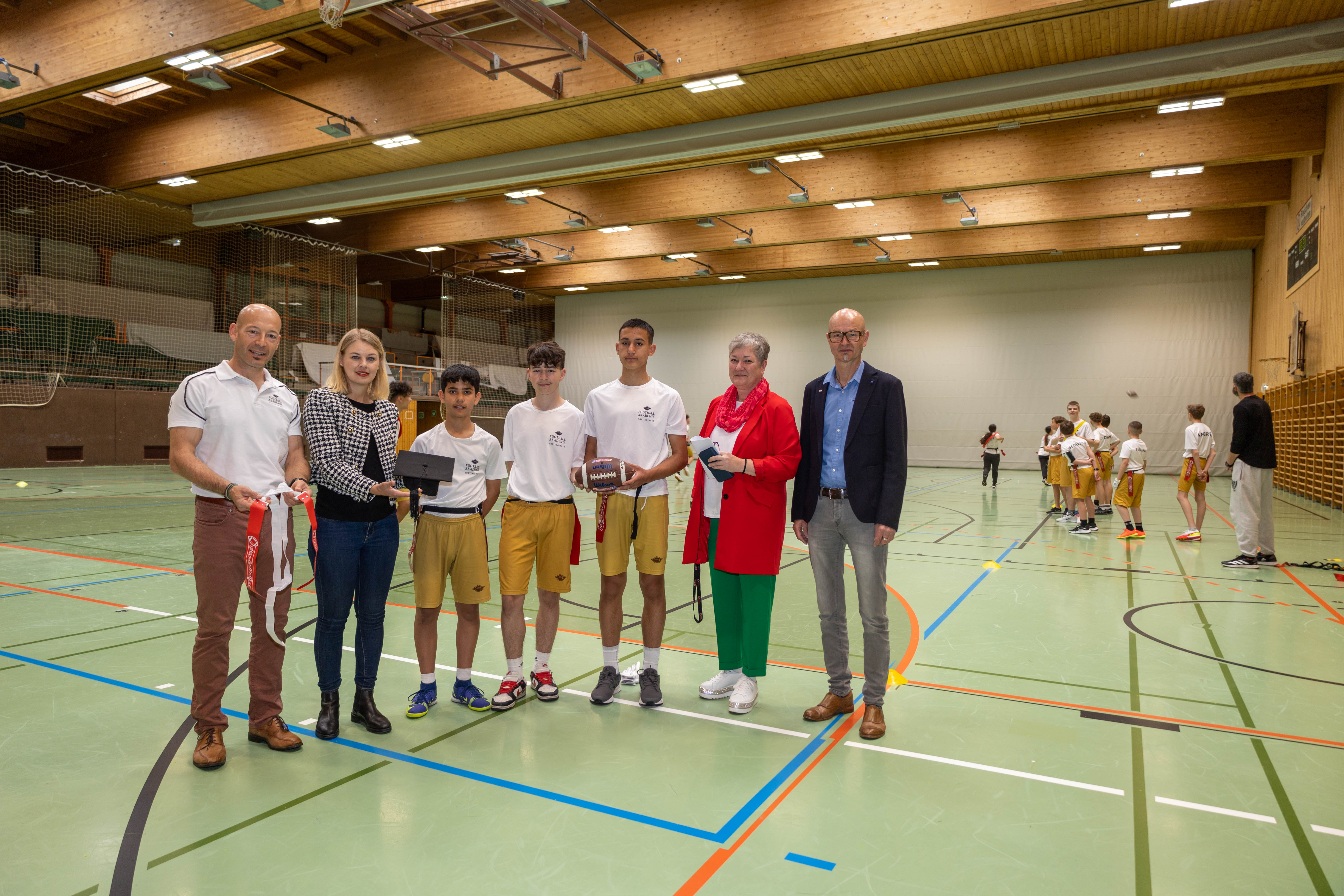 Akademie-Leiter Daniel Dieplinger, Stadträtin Elisabeth Mayr, Schuldirektorin Sabine Rainer und Amtsleiter Werner Leithmayer besuchten die Burschen Milad, Simon und Arslancan (v. l. n. r.) und ihre Klasse beim Football-Training.