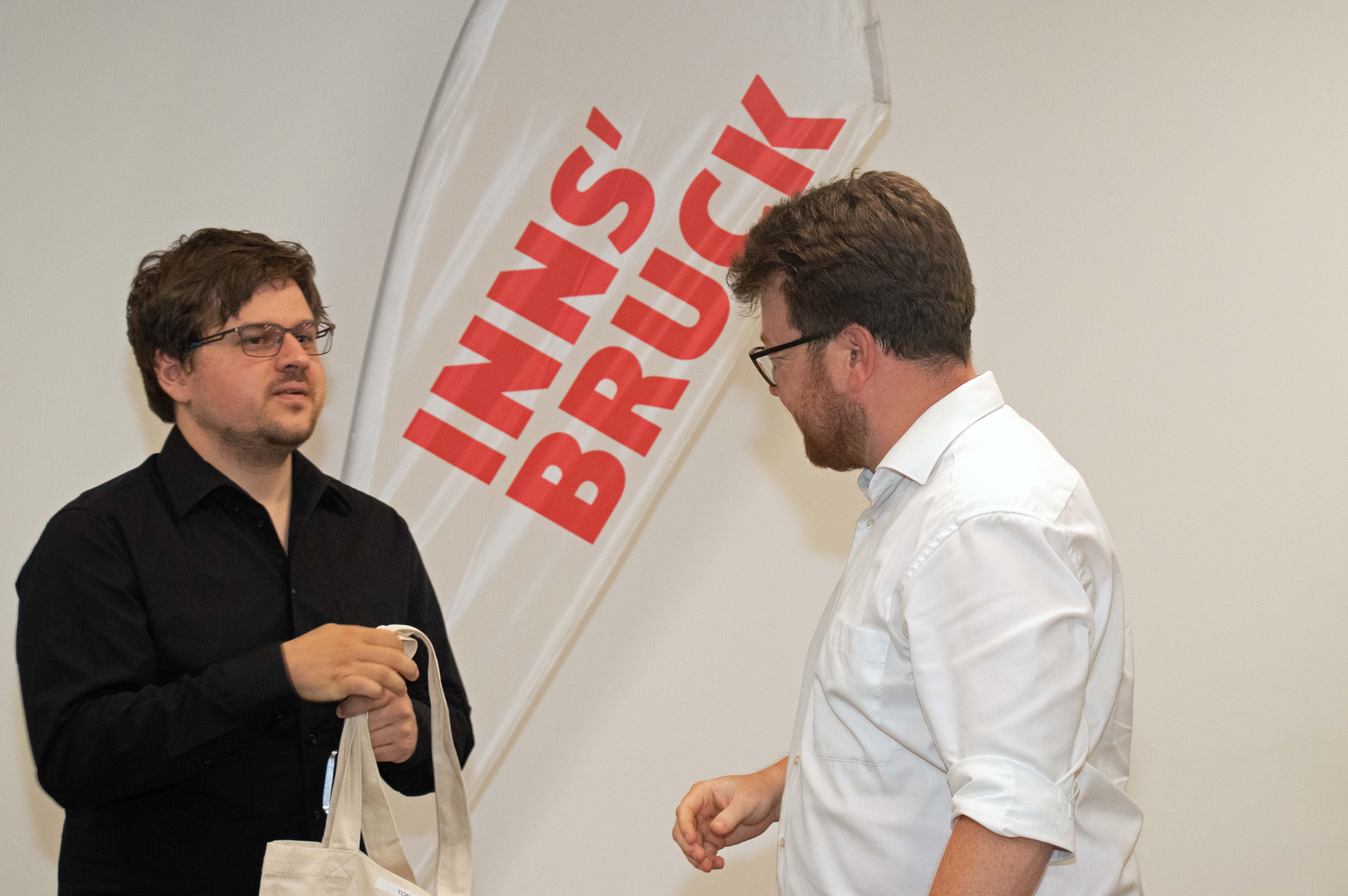 Gemeinderat Benjamin Plach (r.) übergibt eine der neuen Wohnungen an einen Mieter.