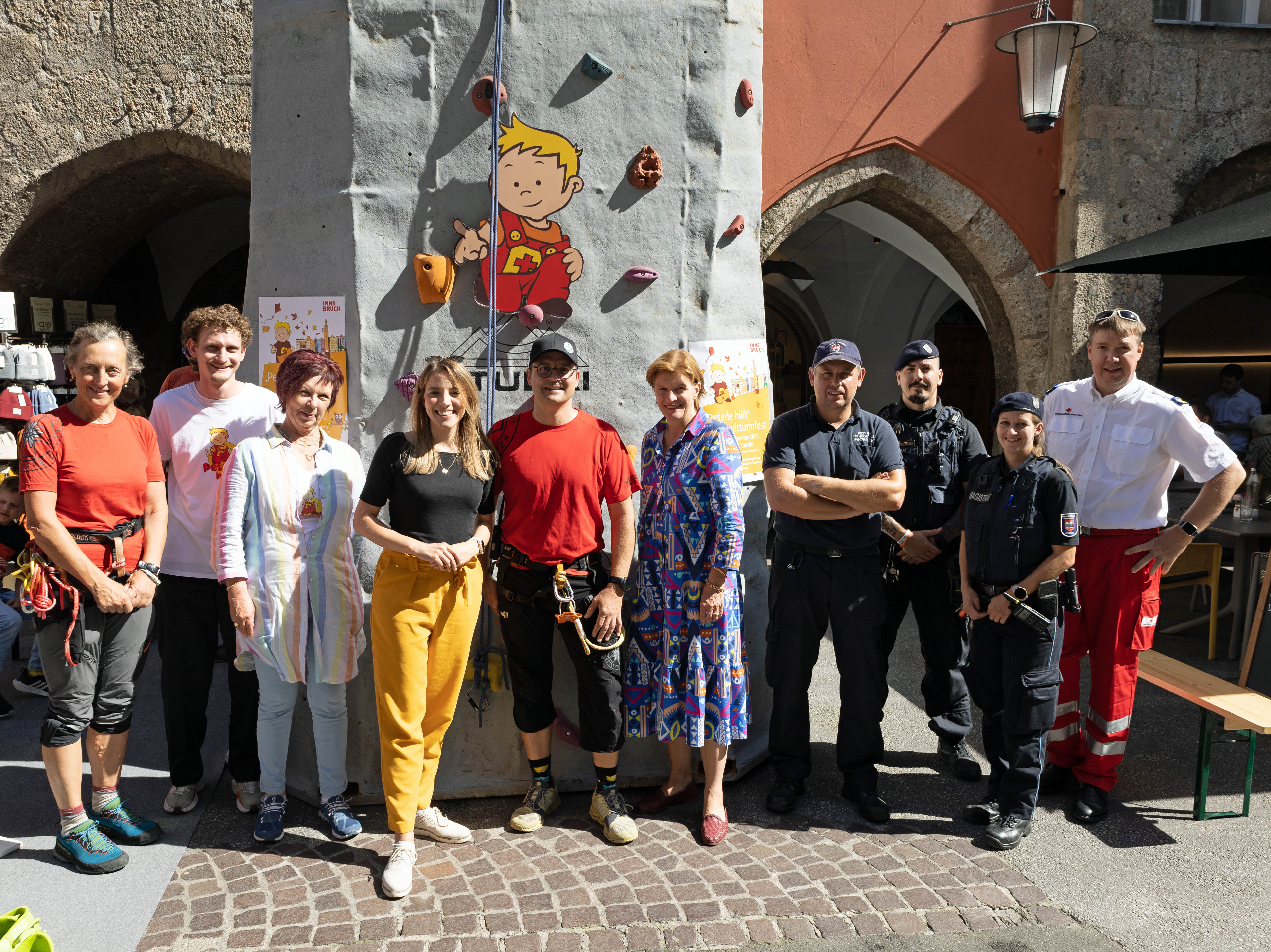 Stadträtin Christine Oppitz-Plörer (5.v.r), Innsbruck-Tourismus-Geschäftsführerin Barbara Plattner (4.v.l.) und Referentin Uschi Klee (Frauen und Generationen, 3.v.l.) freuen sich mit VertreterInnen der teilnehmenden Einsatzorganisationen über das „Peterle hilft“-Fest 2023.