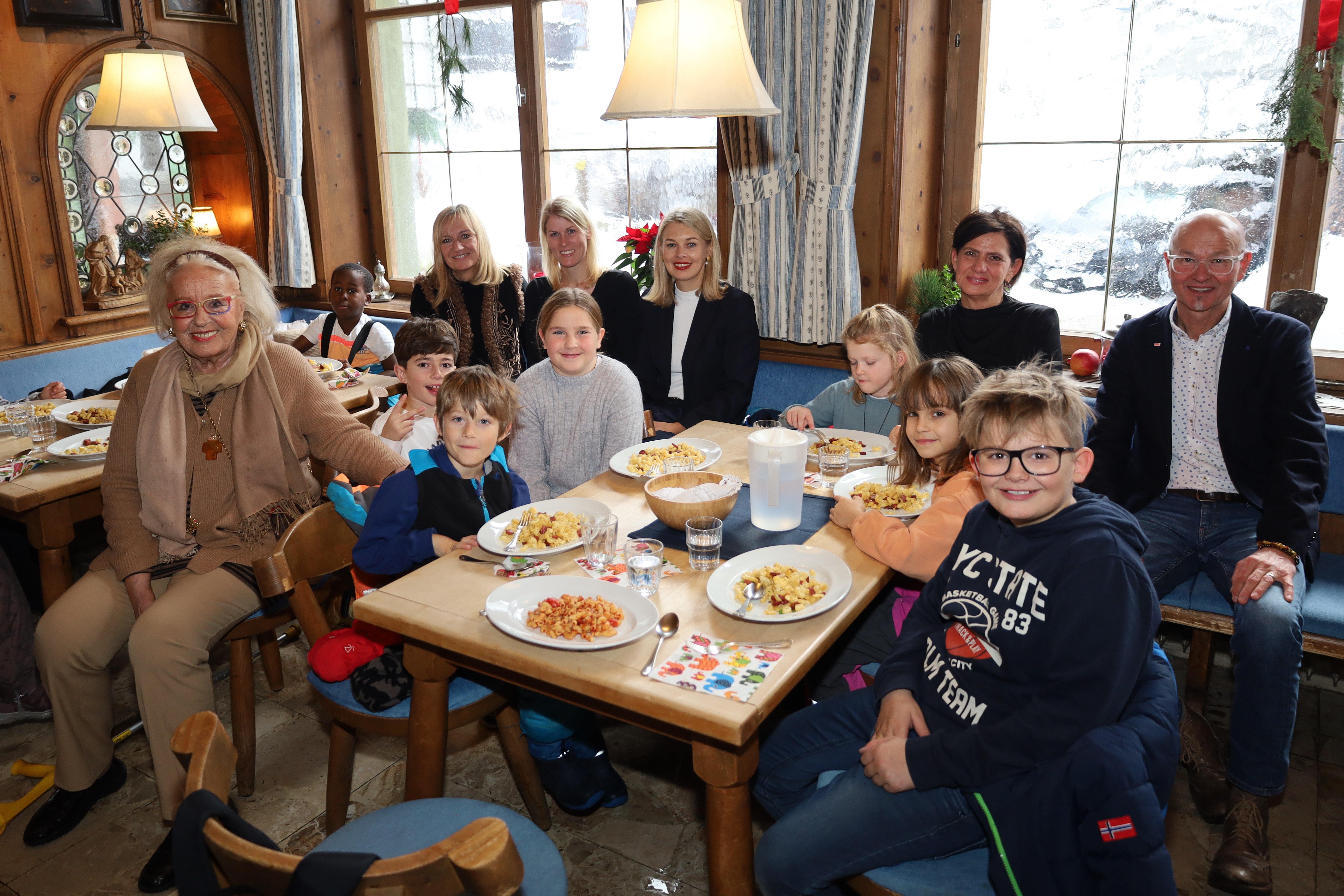 Stadträtin Elisabeth Mayr (7.v.r.) und Amtsvorstand Werner Leithmayer (r.) freuen sich mit den Volksschulkindern, den Lehrerpersonen und dem Ägidihof-Team über den Mittagstisch für die Tagesbetreuung der VS Igls-Vill.
