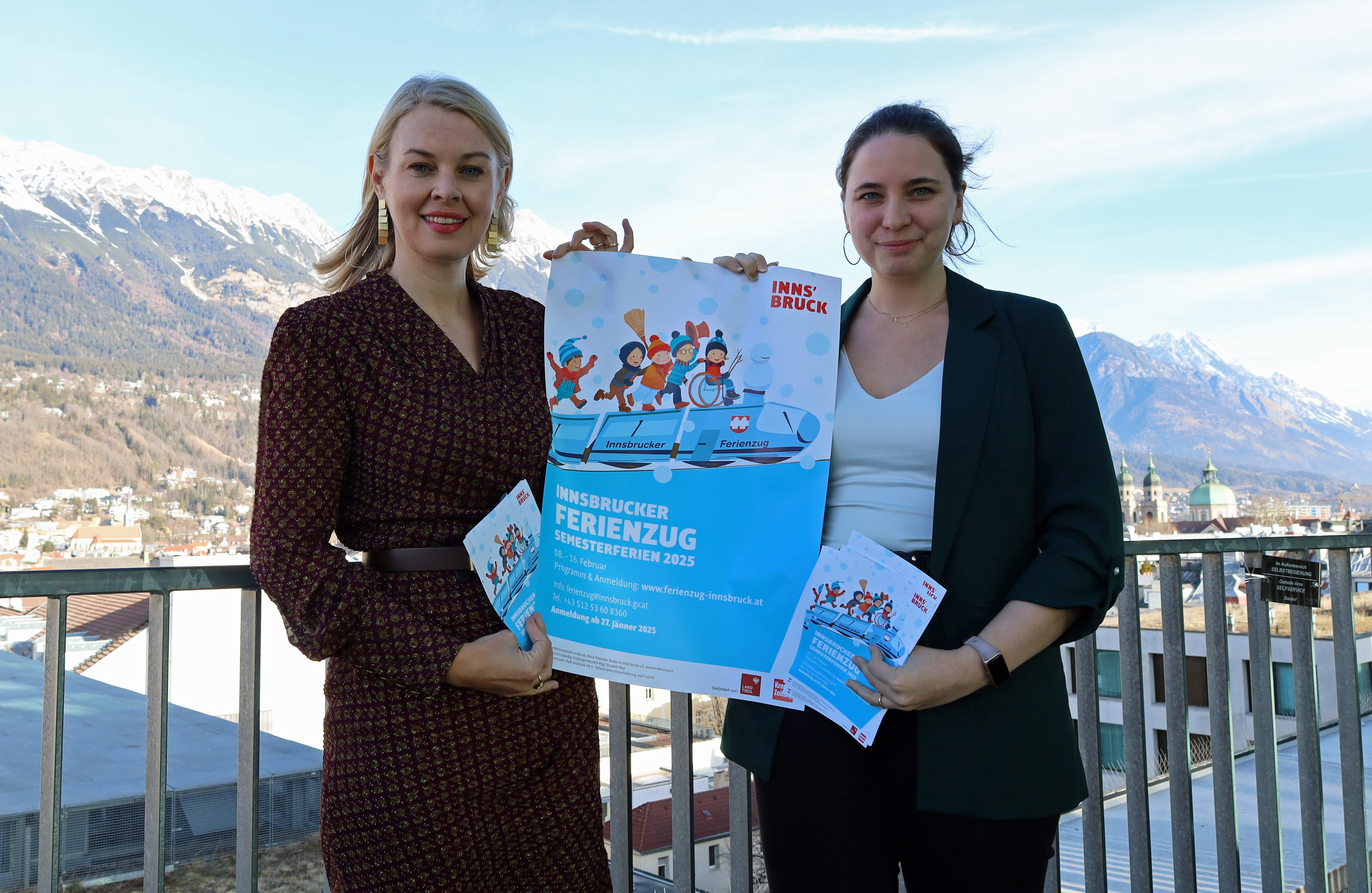 Vizebürgermeisterin Elisabeth Mayr und Eva Pichler (re.) präsentieren den Ferienzug-Fahrplan für Feber 2025.