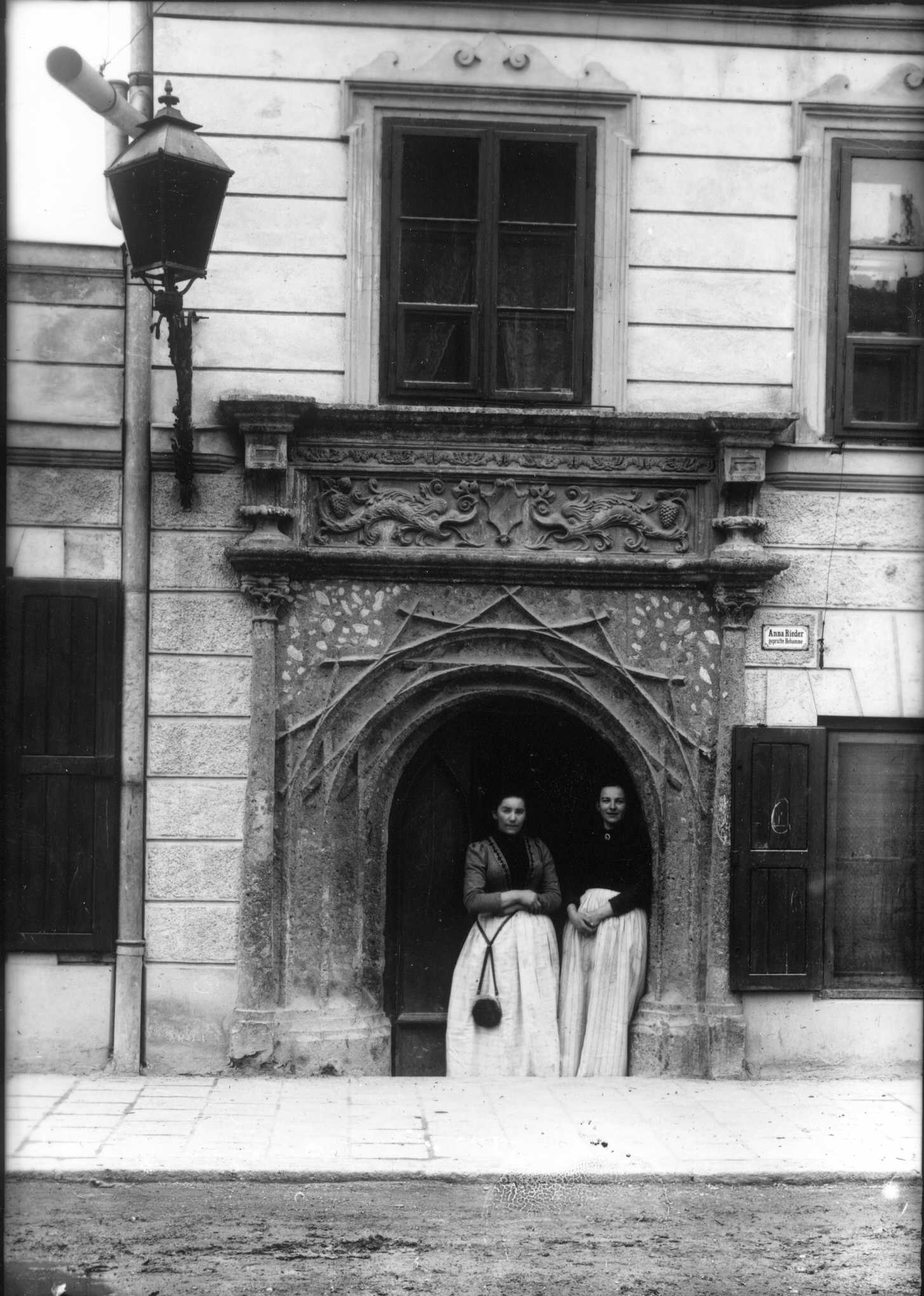 Zwei Hebammen vor der Tür der „geprüften Hebamme“ Anna Rieder in der Innstraße 85, ca. 1901–1906.