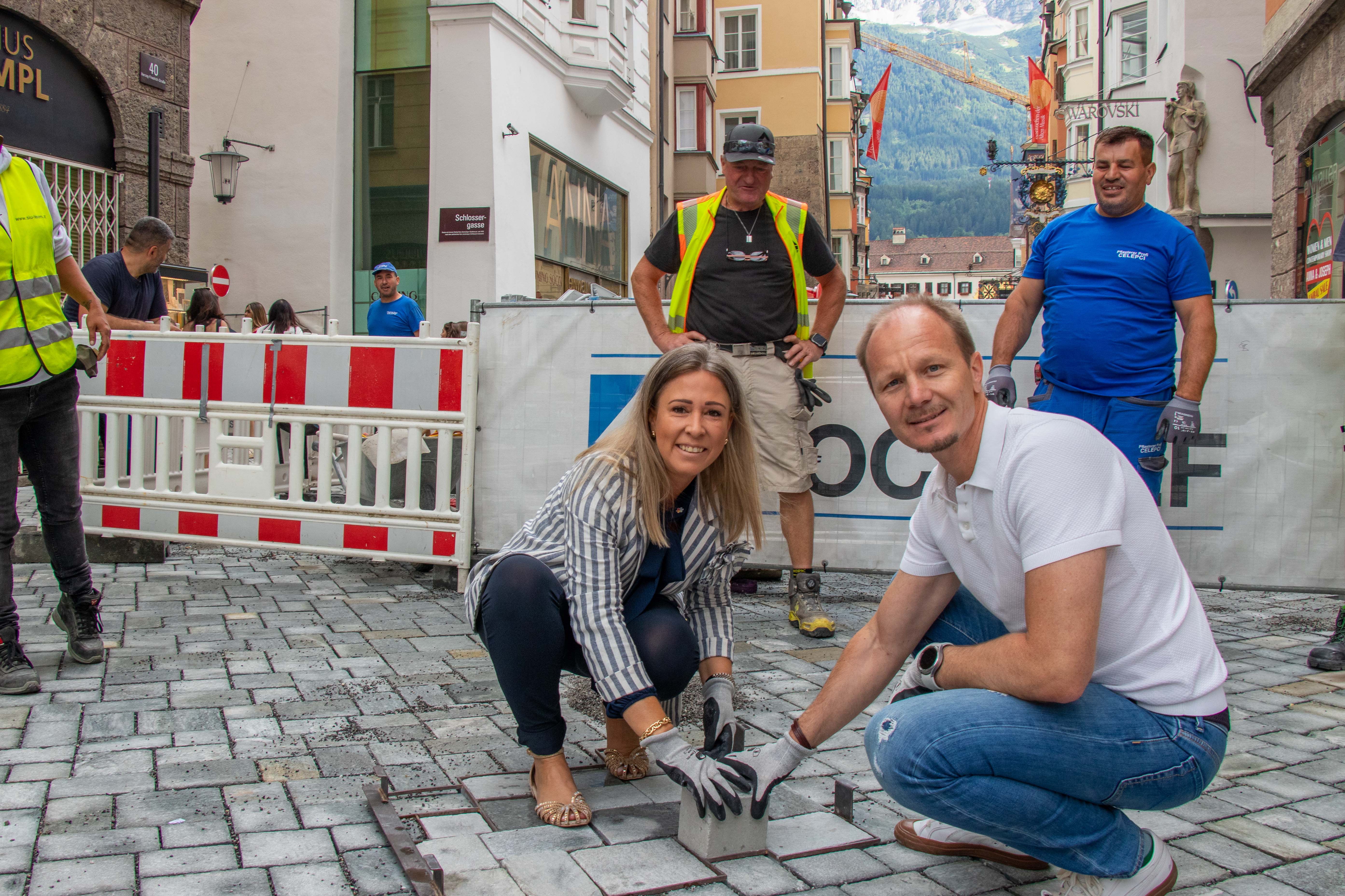 Bürgermeister Johannes Anzengruber und Stadträtin Mariella Lutz setzen gemeinsam den letzten Pflasterstein in der Herzog-Friedrich-Straße und besiegeln damit den Abschluss der Arbeiten in der Innsbrucker Altstadt.