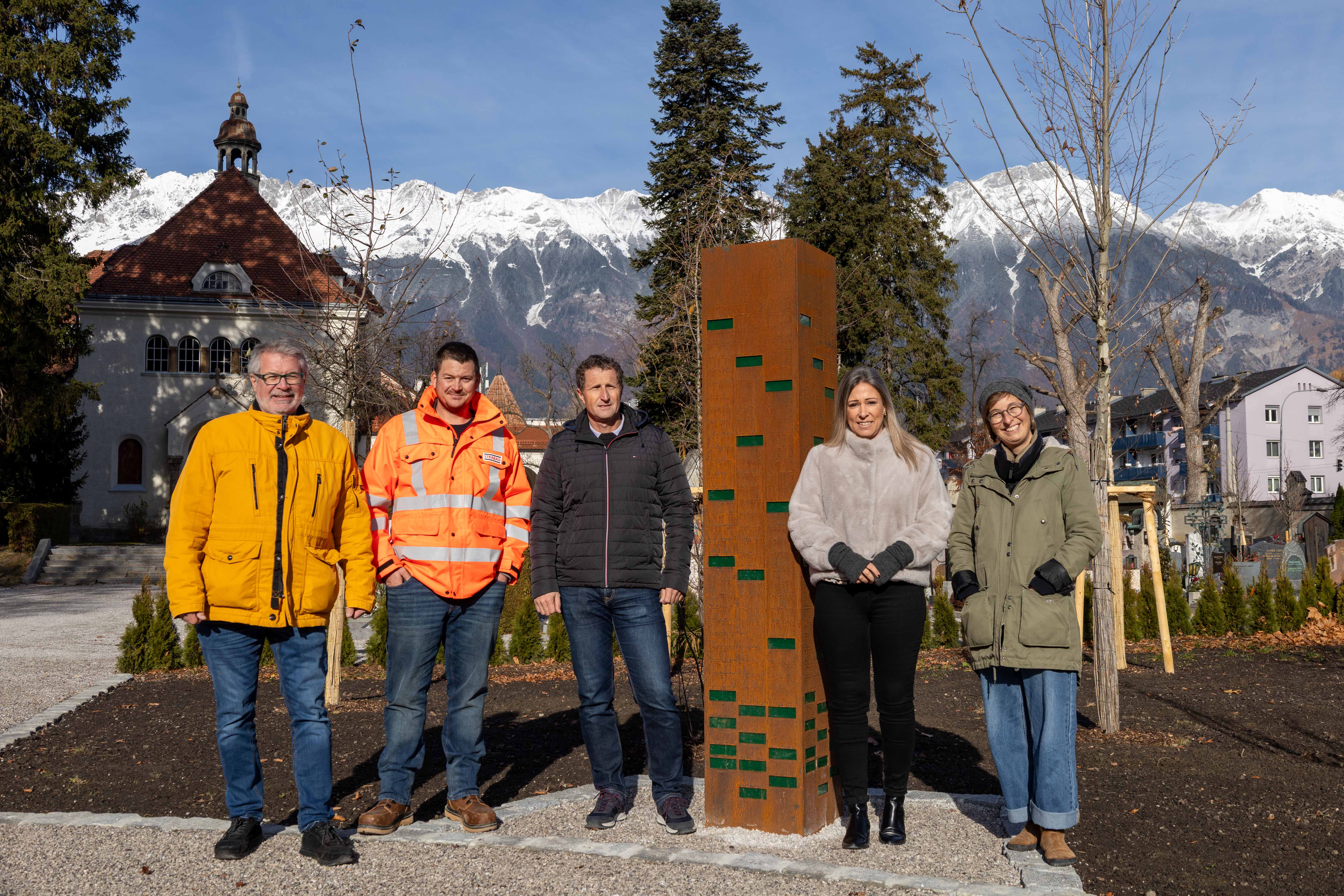 Stadträtin Mariella Lutz (2.v.r.) freut sich gemeinsam mit (v.l.n.r.) Referent Alexander Legniti, Polier Christoph Kratzer (STRABAG), Amtsvorstand Thomas Klingler (Grünanlagen) und Landschaftsplanerin Lisa Stöllnberger (Grünanlagen – Planung und Bau) über die innovative Baumgrabstätte am Pradler Friedhof.