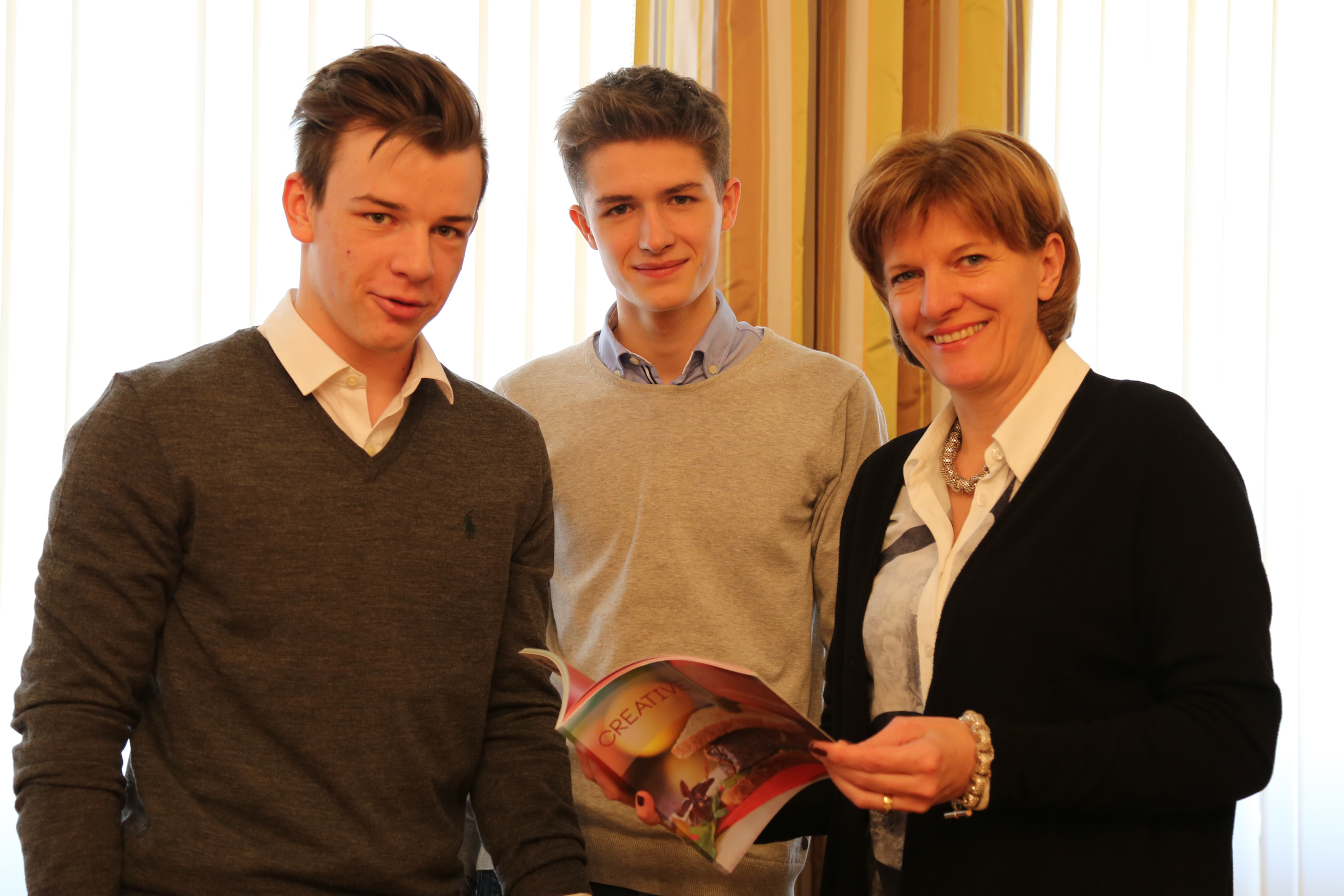 Paul Triendl und Simon Vötter von der „Junior Company - Creative Cooking“ präsentieren Bürgermeisterin Christine Oppitz-Plörer stolz ihr Kochbuch.