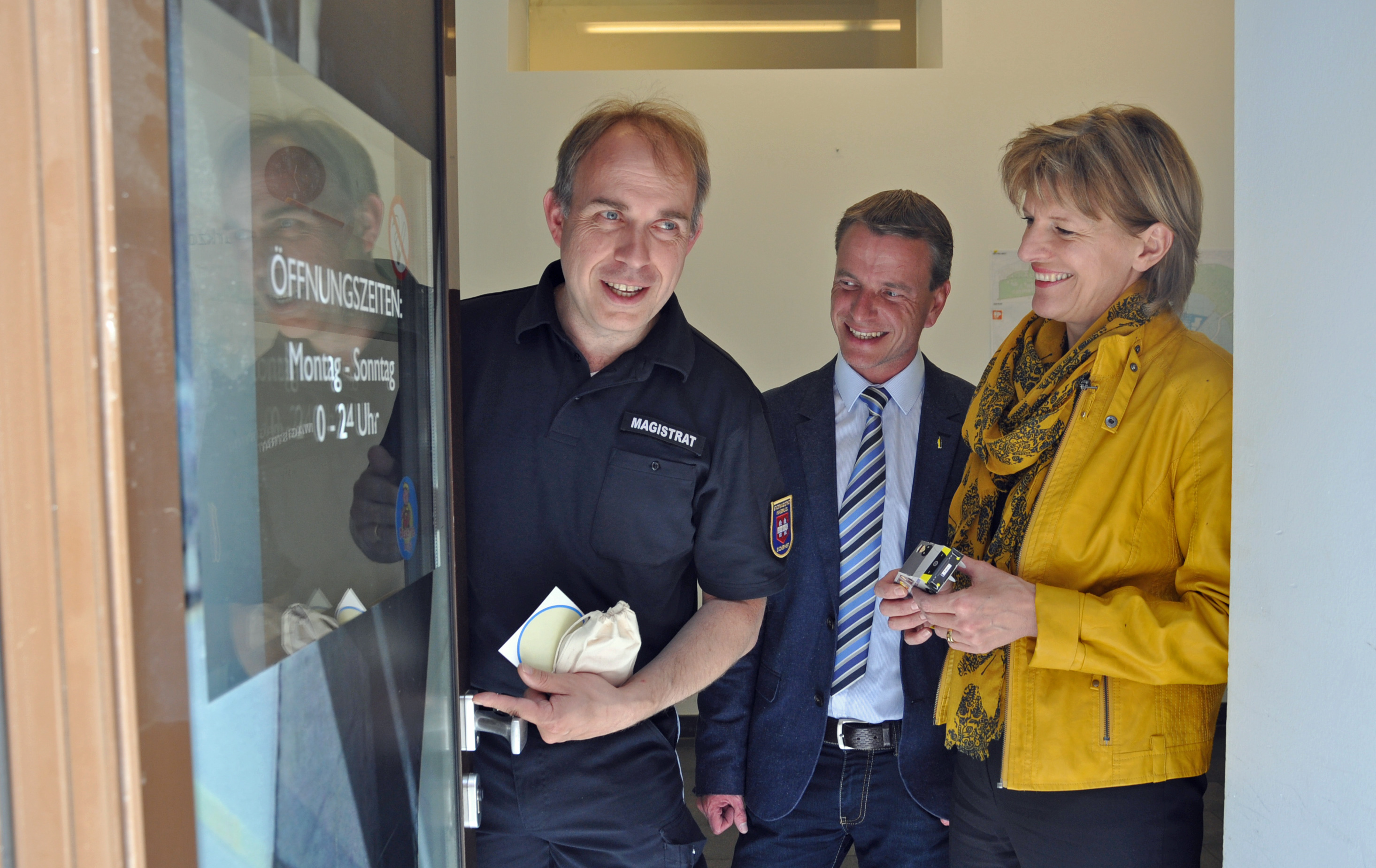Amtsvorstand Elmar Rizzoli (Allgemeine Sicherheit und Veranstaltungen), Vizebürgermeister Christoph Kaufmann und Bürgermeisterin Christine Oppitz-Plörer (v. l.) brachten an der Eingangstür der „MÜG-Zentrale“ in der Salurnerstraße einen „Peterle hilft“-Aufkleber an.