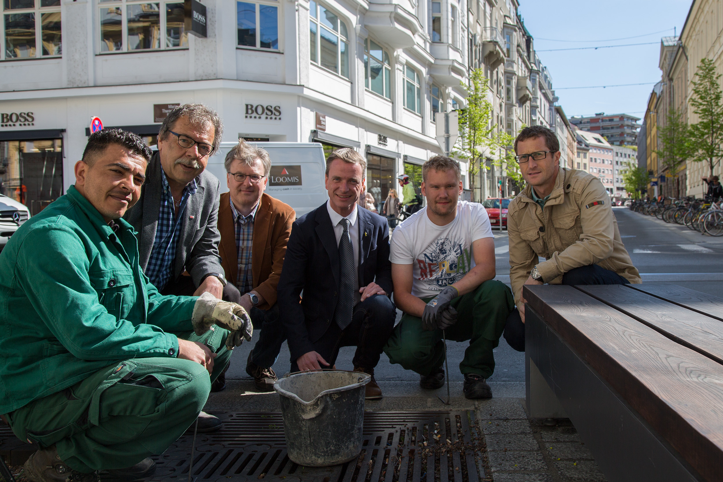 Zwei städtische Mitarbeiter reinigten gemeinsam mit Stadtrat Gerhard Fritz, Amtsvorstand Josef Mühlmann, Vizebürgermeister Christoph Kaufmann (ab 2.v.l.) und Amtsvorstand Ing. Thomas Klingler (r.) eine Baumscheibenabdeckung.