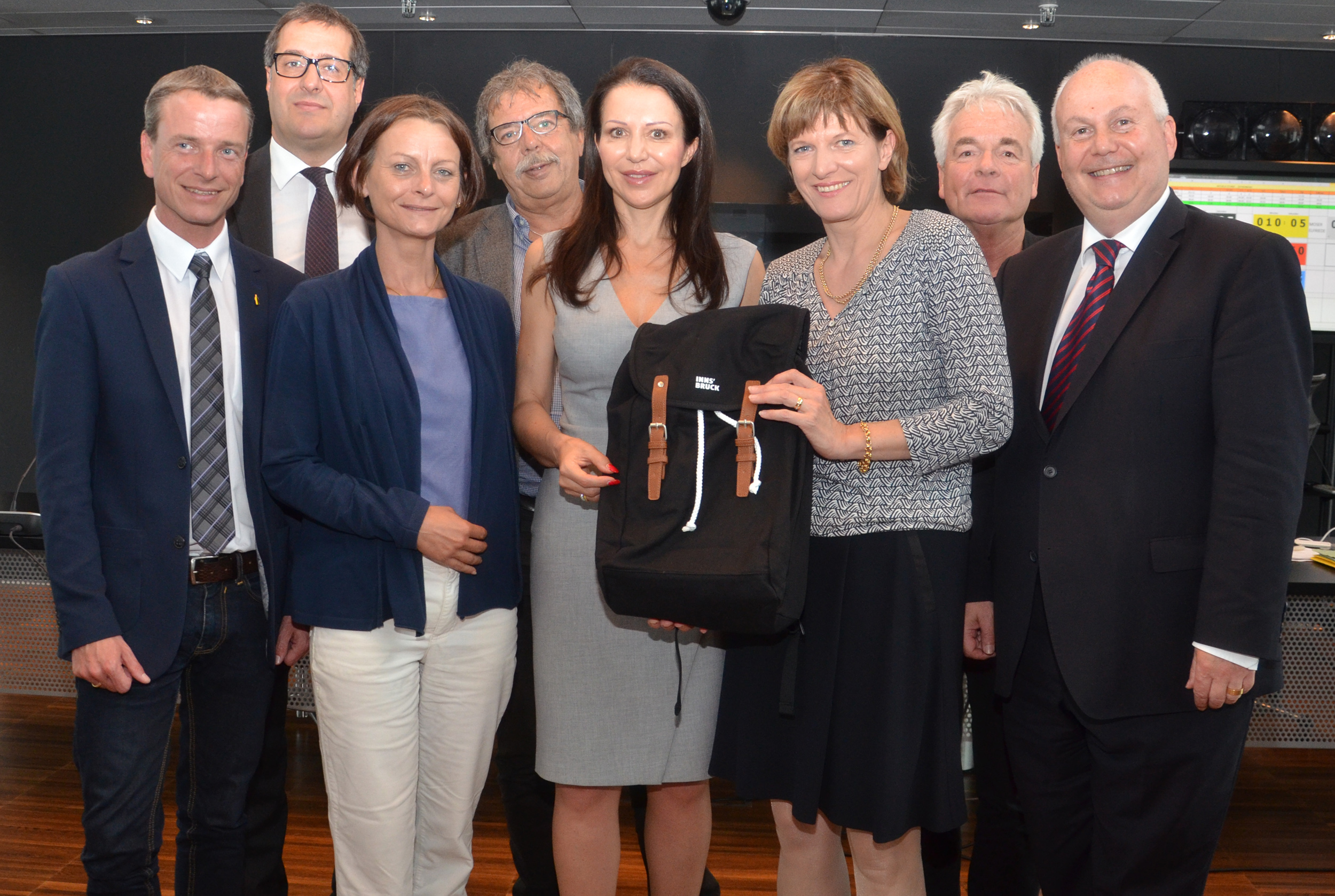 Bürgermeisterin Christine Oppitz-Plörer übergab gemeinsam mit Vizebürgermeisterin Sonja Pitscheider (3.v.l.), Vizebürgermeister Christoph Kaufmann (l.), StR Franz X. Gruber (hinten l.), StR Gerhard Fritz (hinten 2.v.l.), StR Ernst Pechlaner (hinten r.) und StR Andreas Wanker (r.) als Dankeschön für ihren Vortrag einen Innsbruck-Rucksack an Barbara Kappel.