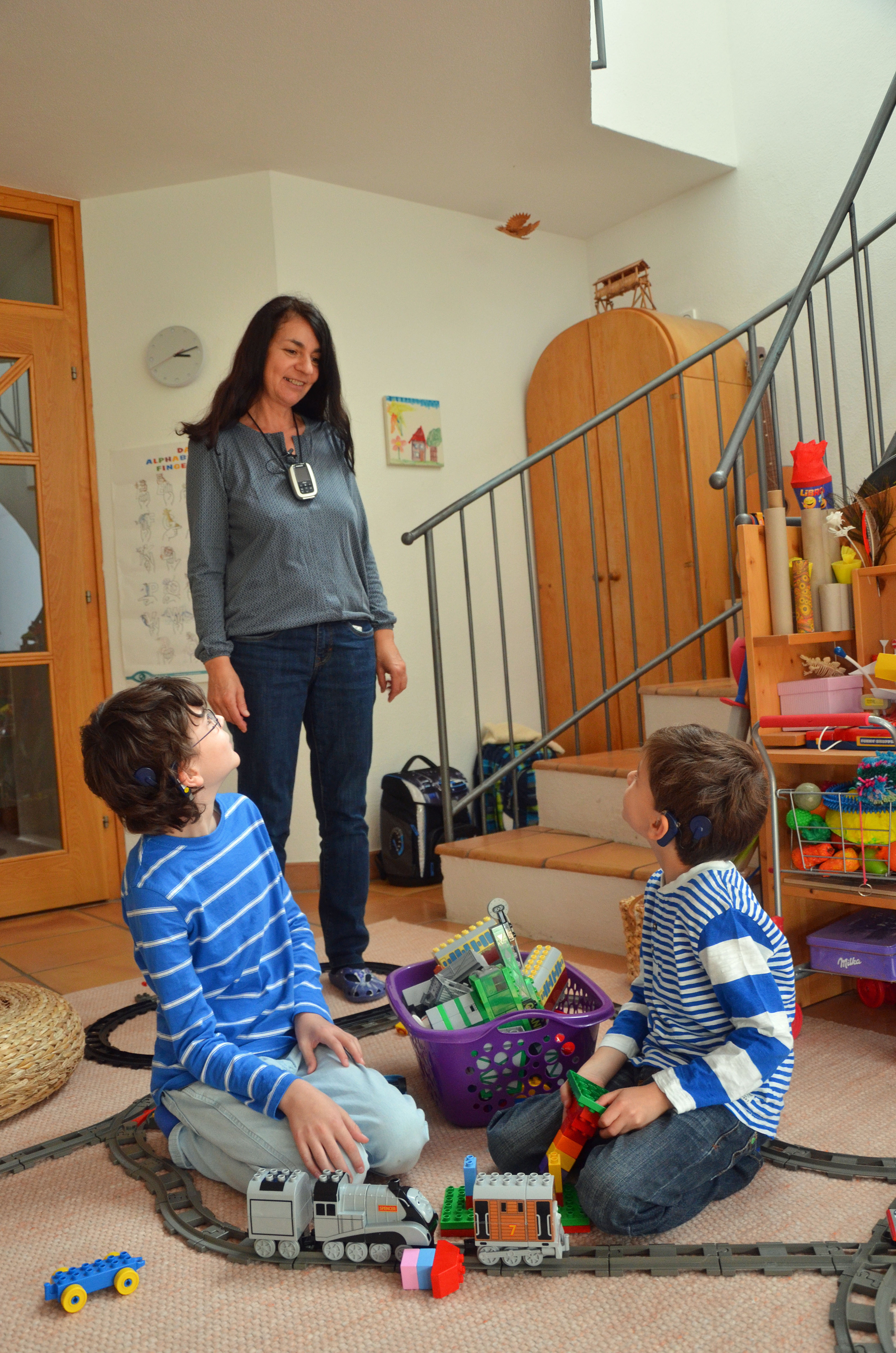 Beim Hausbesuch zeigte Mama Gabriele mit ihren beiden Söhnen, wie die FM-Anlage – die sie um den Hals trägt – funktioniert.