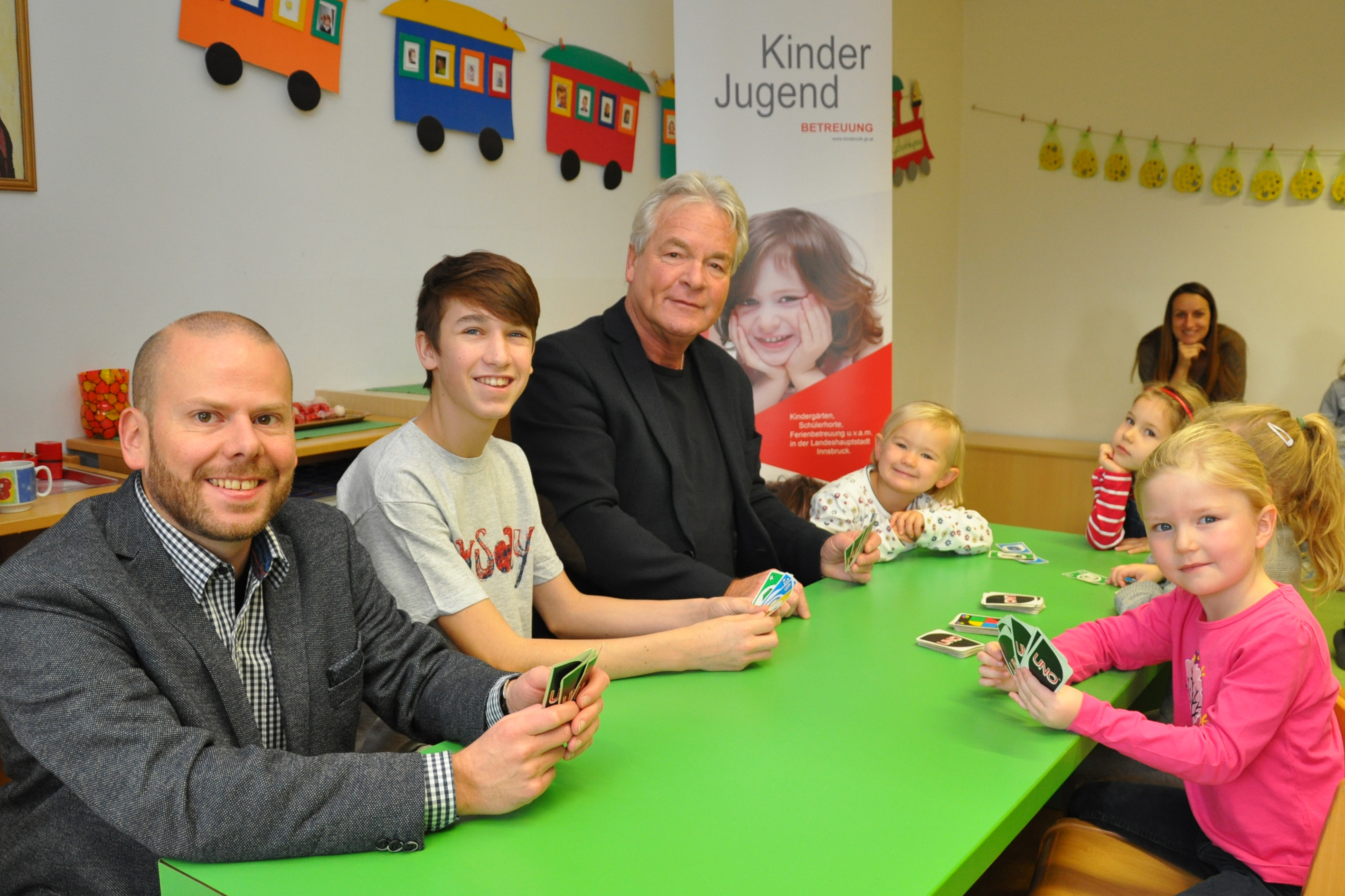 Boys‘-Day-Koordinator Gotthard Bertsch (l.) und Stadtrat Ernst Pechlaner (Mitte) statteten dem Kindergarten Allerheiligen einen Besuch ab. Dort schaute sich Vinzenz (2.v.l.) den Beruf des Kindergartenpädagogen an. Mit den Kindergartenkindern lieferten sie sich spannende UNO-Duelle.