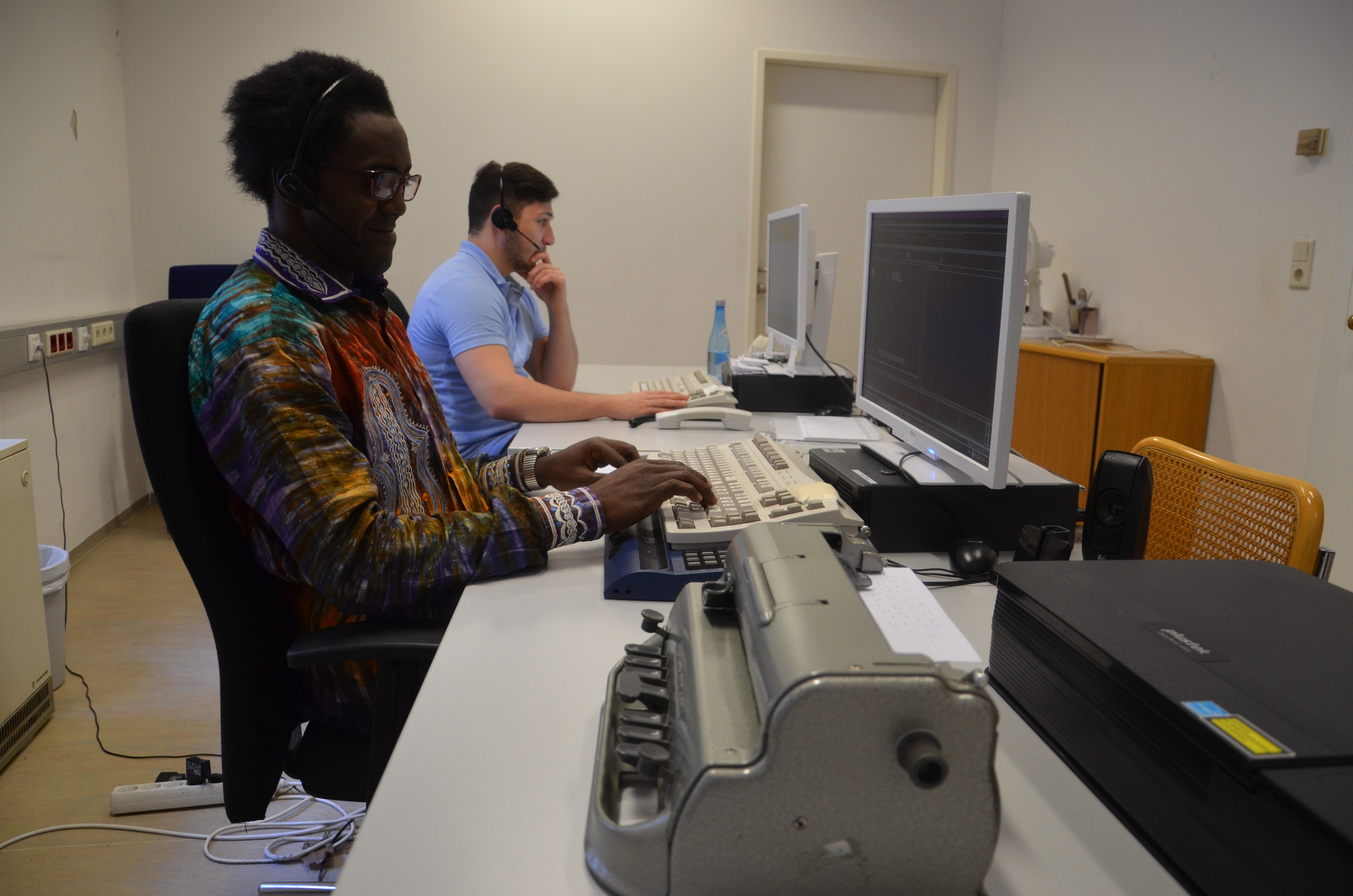 Die beiden schwer sehbehinderten Mitarbeiter der Telefonvermittlung, Herve Paulin Nomy Ngnoma (l.) und Hakan Özer, sind Teil der vielfältigen Belegschaft des Stadtmagistrats.