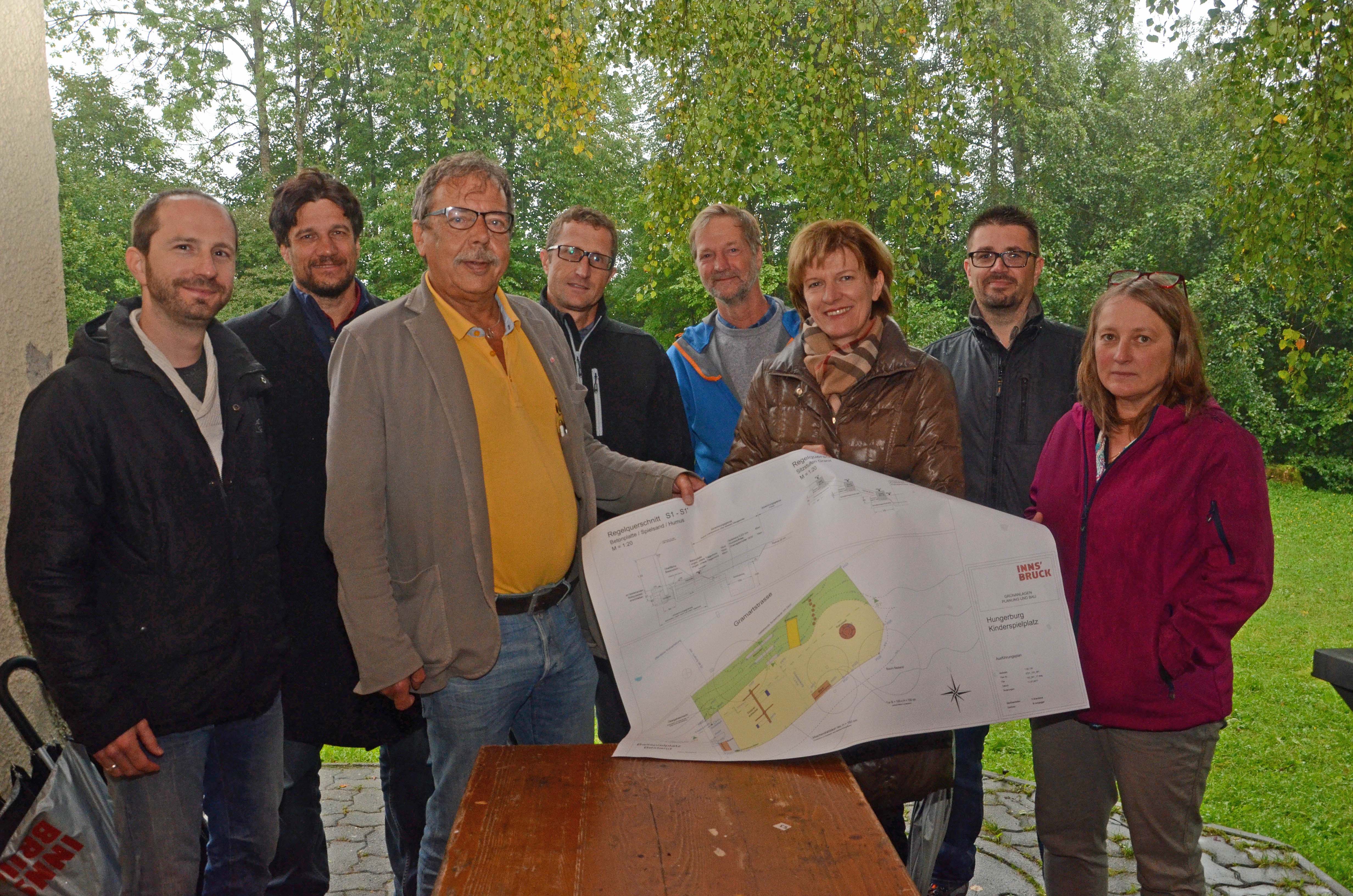 Vorstand Simon Grießenböck (Kinderfreunde), Obmann Hanns-Christoph Nägerl (Verein Baukultur & Lebensraum Hungerburg), Stadtrat Gerhard Fritz, Amtsvorstand Thomas Klingler (Grünanlagen), Peter Brandsma (Grünanlagen – Planung und Bau), Bürgermeisterin Christine Oppitz-Plörer, Stefan Plenk (Berger & Brunner BaugmbH) und Barbara Bloch (v. l.) nahmen den Plan des neuen Spielplatzes auf der Hungerburg gemeinsam unter die Lupe.