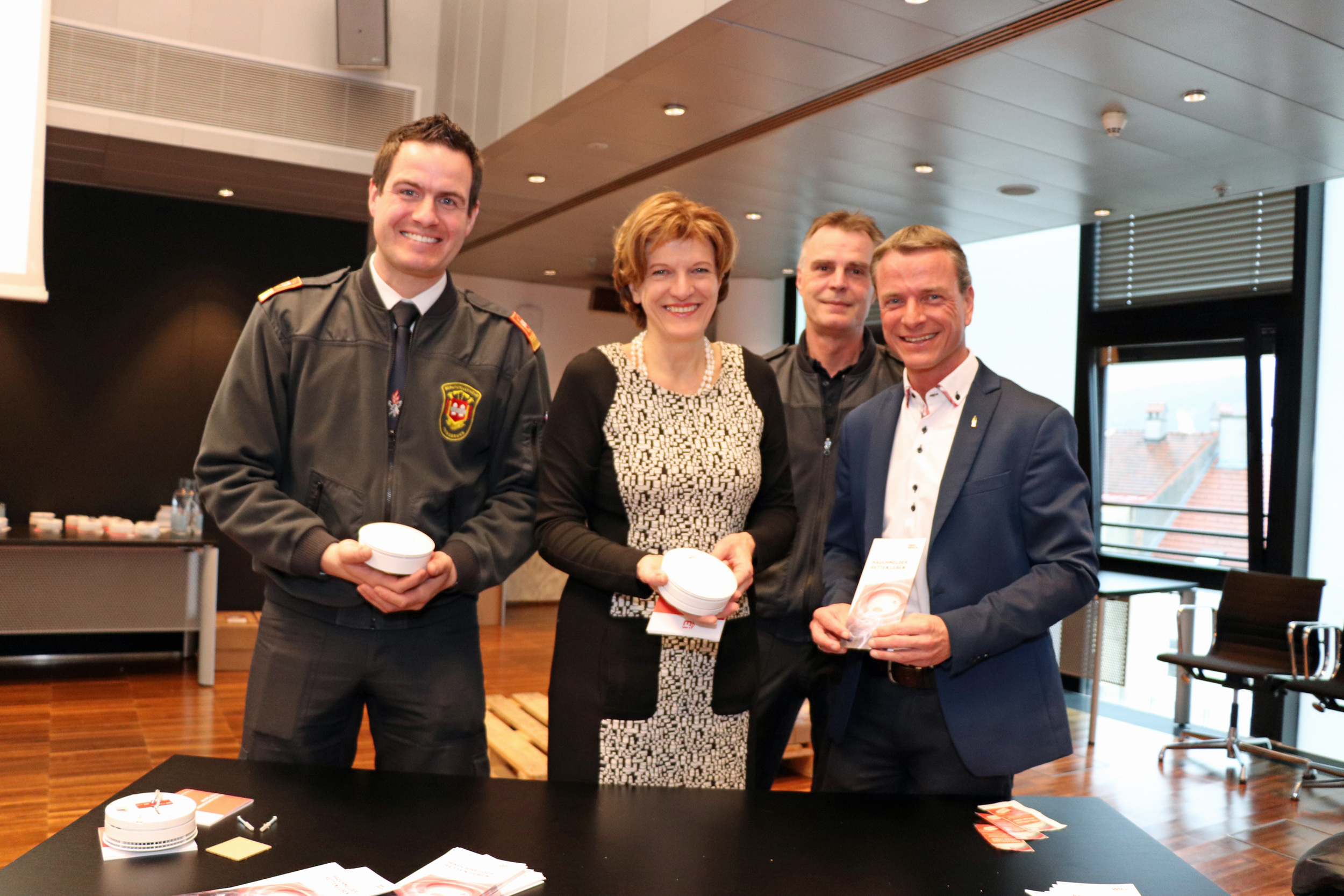 Branddirektor Helmut Hager, Bürgermeisterin Christine Oppitz-Plörer, Vizebürgermeister Christoph Kaufmann (v.l.) verteilten mit Hansjörg Egger (2.v.r.) im Plenarsaal Rauchmelder an InnsbruckerInnen.